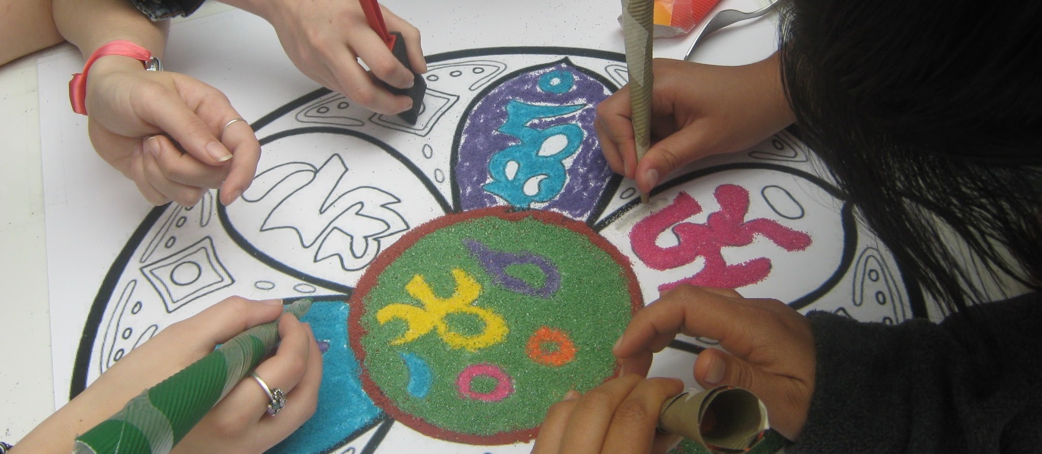 Manos pintando un mandala de colores durante una actividad del Centro.