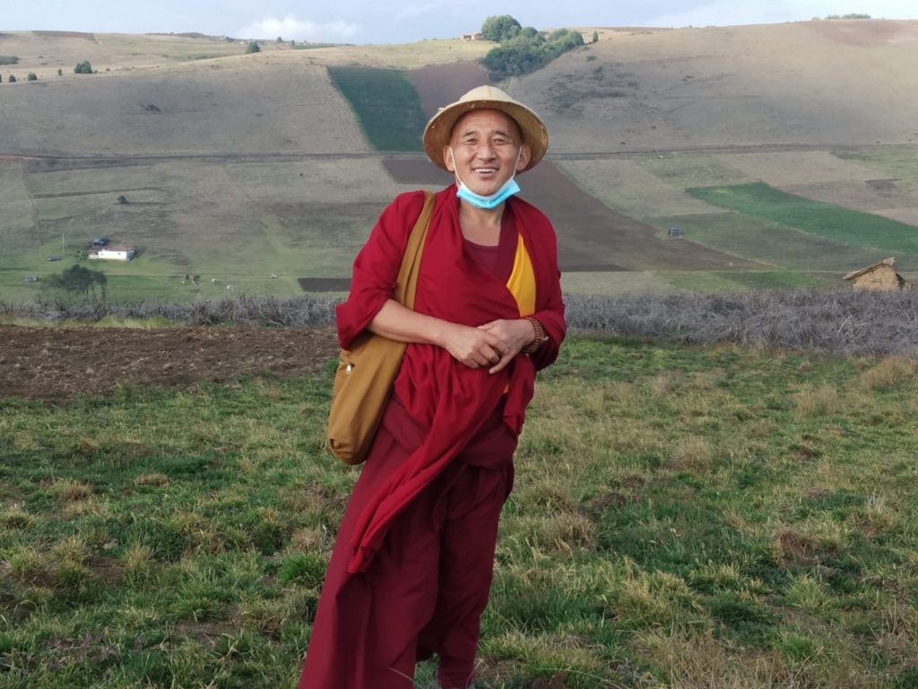 Monje budista con una alpaca en un paisaje de altura.