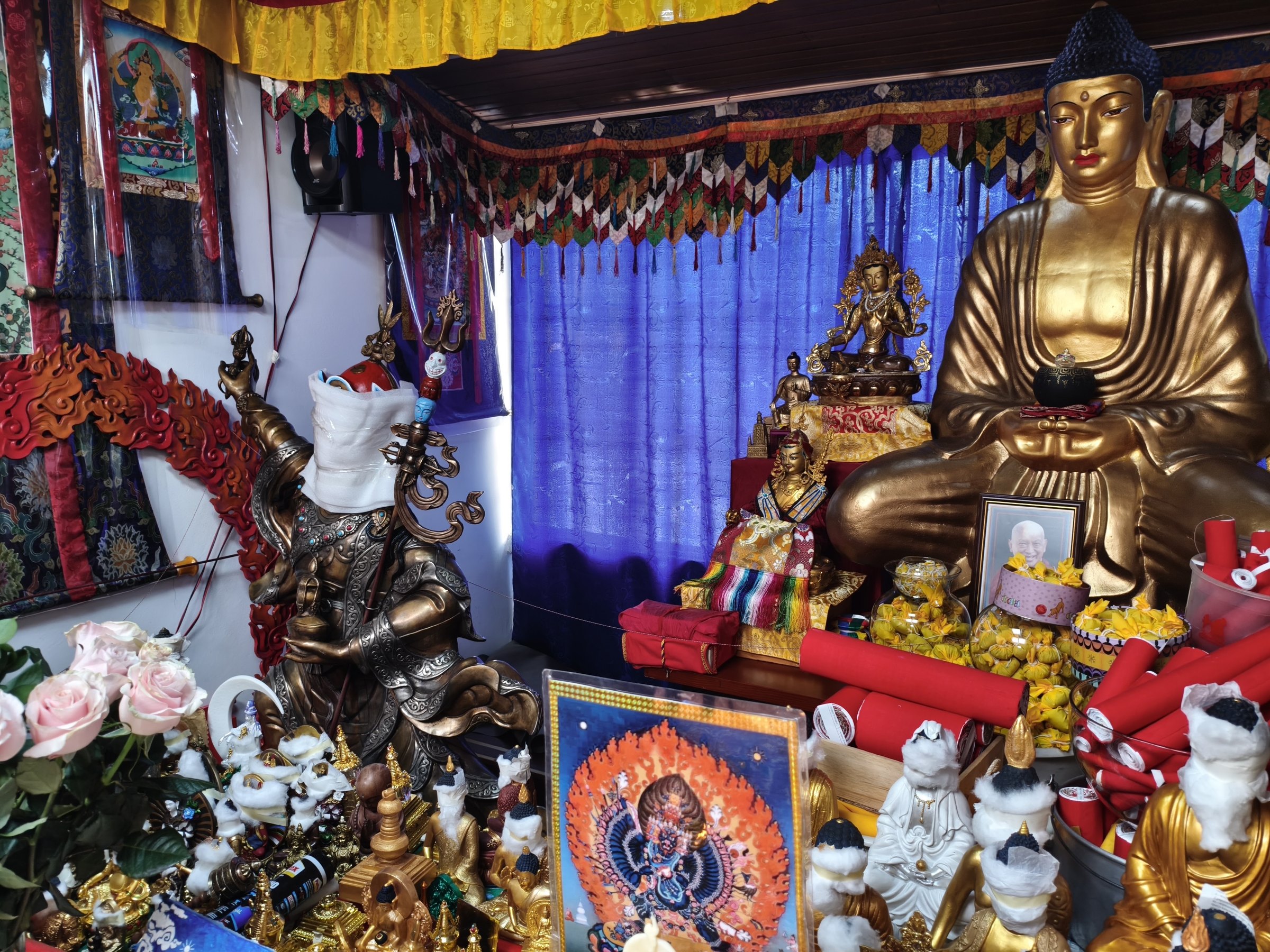 Altar de la gompa con la estatua dorada de Buda y las ofrendas.