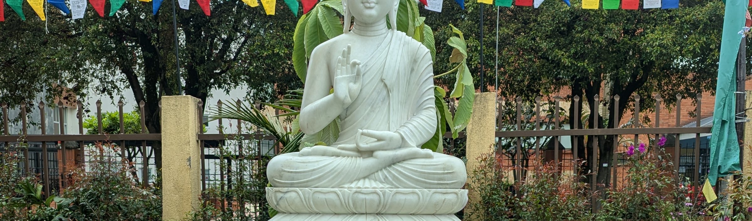 El jardín de la sede del Centro Yamantaka, con la estatua blanca del Buda, la fuente y las banderas de oración.