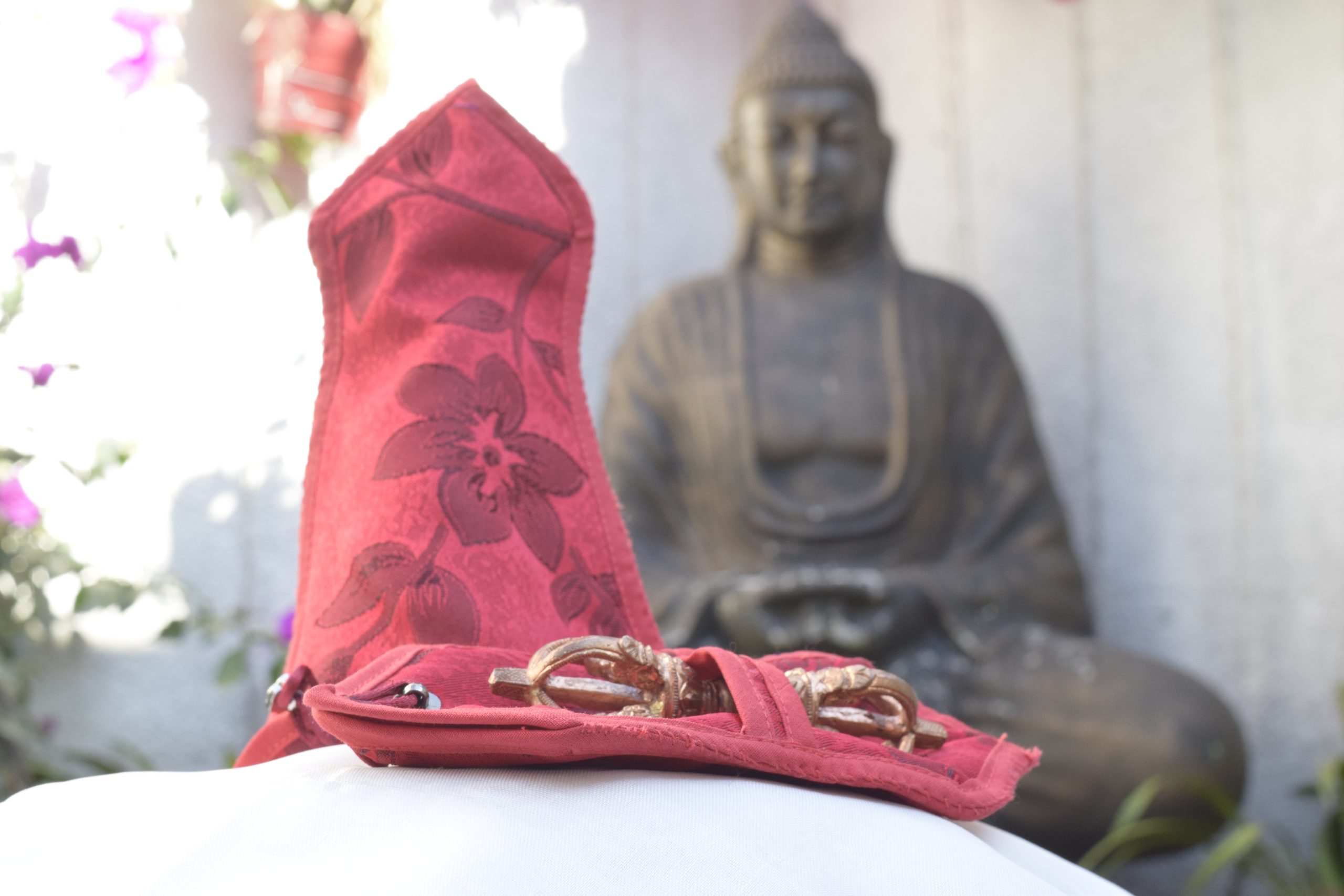Estatua de Buda con un paño rojo y ofrendas doradas.
