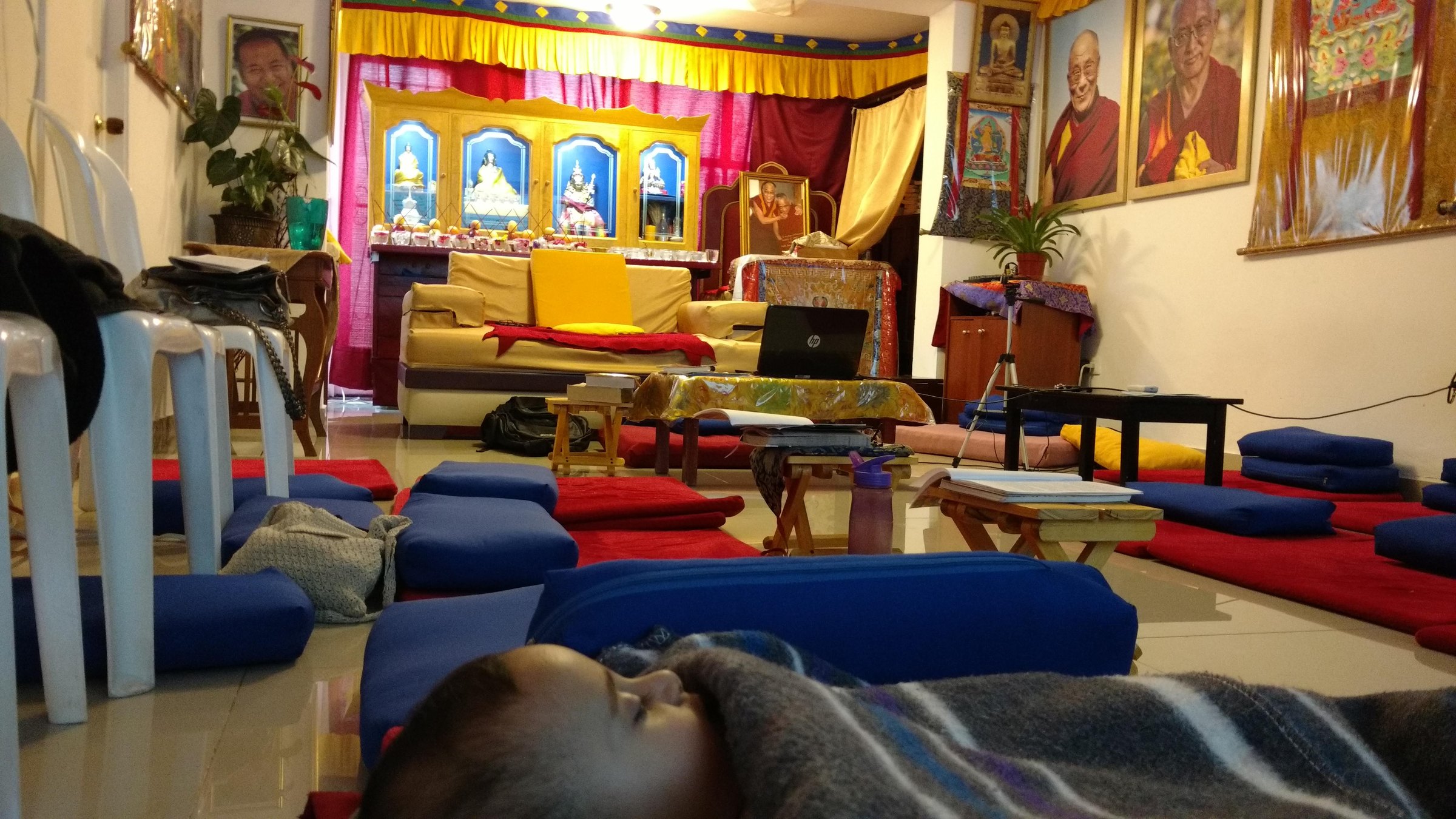 Sala de meditación preparada, con cojines y el altar al fondo.